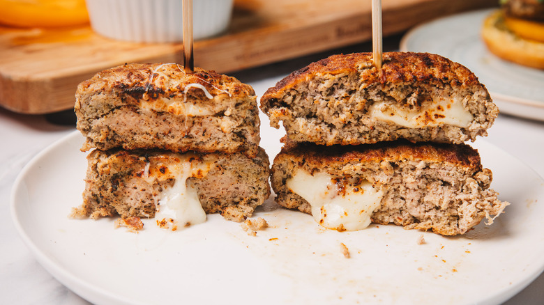 Two stacked pesto turkey burgers cut in half with mozzarella oozing out.
