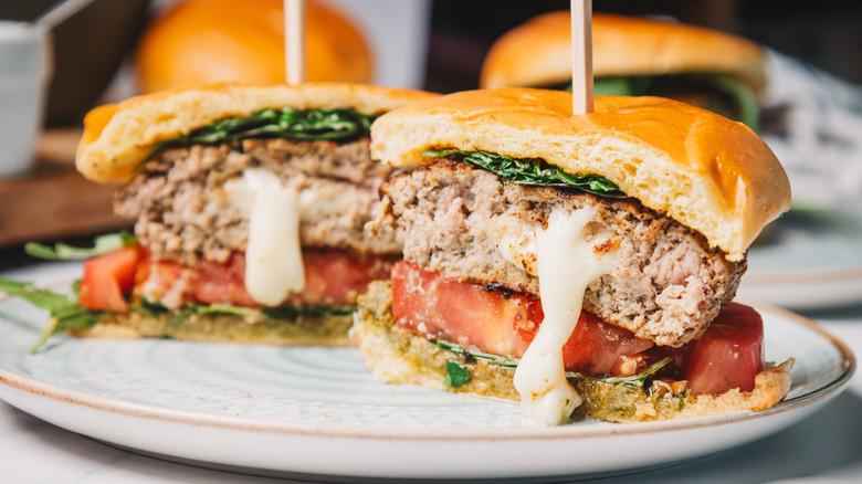 A pesto turkey burger cut in half with mozzarella oozing out.