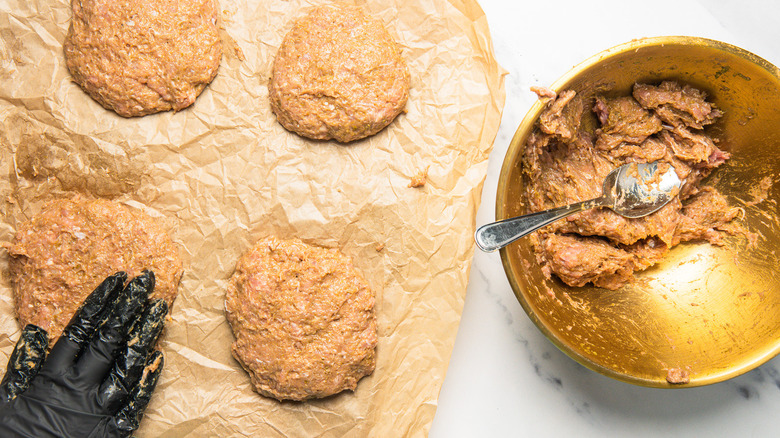 Shaping four raw turkey burgers on baking sheet.