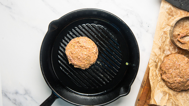 Raw turkey burger in a cast iron grill pan.