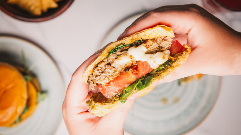 Lifting a pesto turkey burger cut in half.