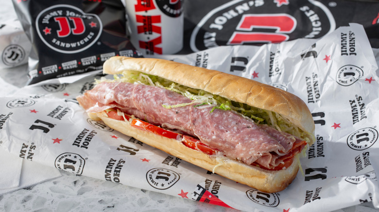 Jimmy John's Italian sandwich with chips and drink in background.