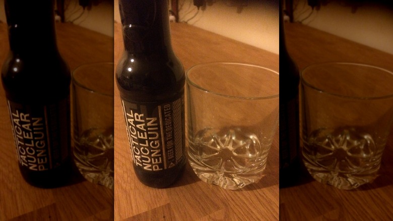 A bottle of Tactical Nuclear Penguin beer next to an empty glass
