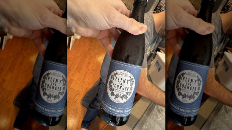 A hand holding a bottle of Pliny the Younger beer