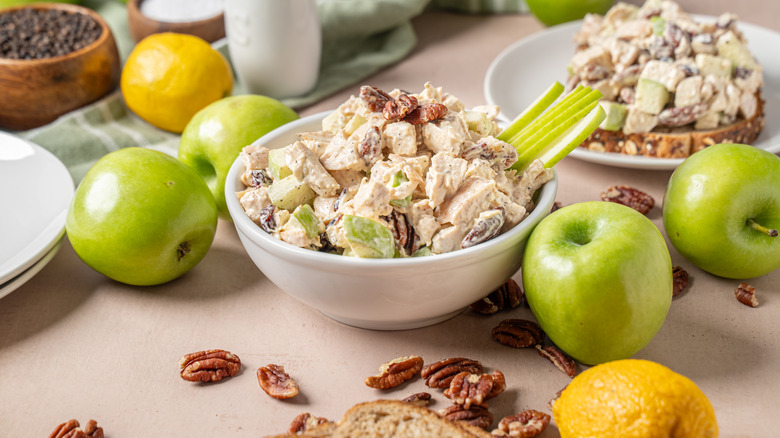 bowl of chicken salad made with apples pictured with green apples