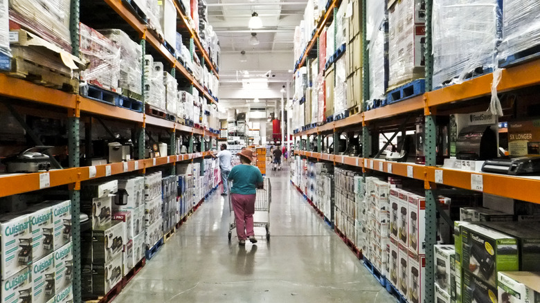 A customer pushing a cart down a Costco aisle