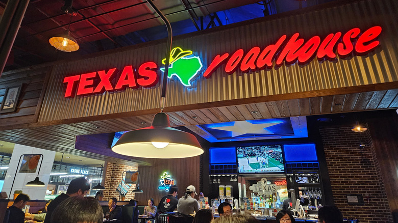 The interior of a Texas Roadhouse with a red neon sign