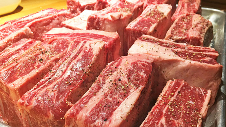 A large pan full of seasoned raw beef short ribs