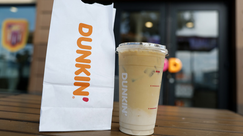 A Dunkin iced coffee and Dunkin bag on an outdoor table
