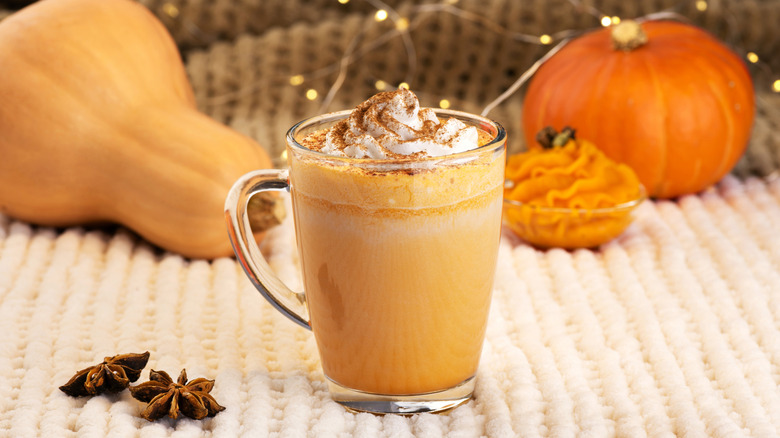 A cream-topped drink in a glass mug, with spices and squash