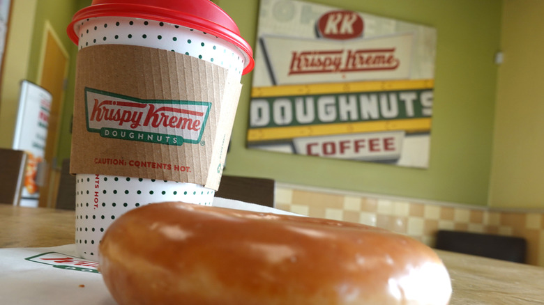 A Krispy Kreme donut and drink on a table in a store