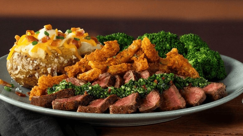 The Chimichurri Filet from Outback Steakhouse beside Blooming Onion Petals, a baked potato, and broccoli.