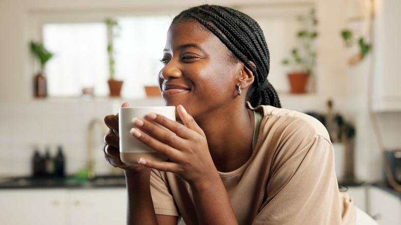 Person smiling holding white mug of coffee