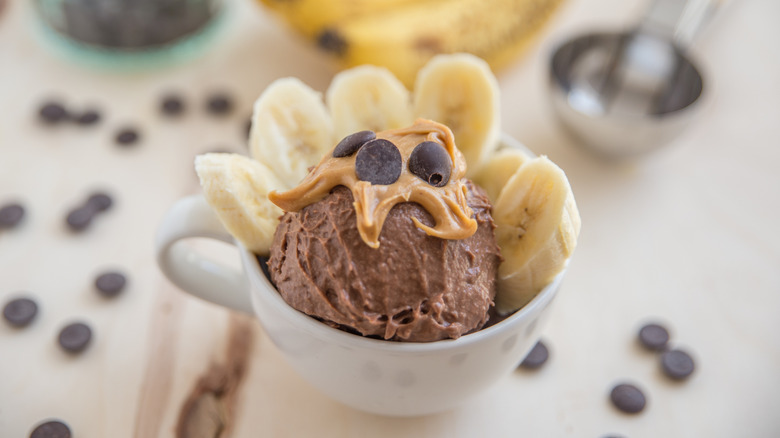 A scoop of chocolate ice cream topped with peanut butter, chocolate chips, and banana slices