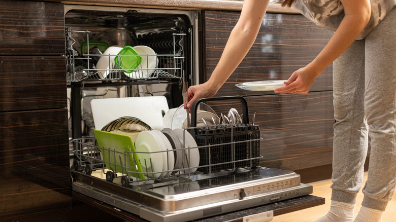 Person loading dirty dishes into an open dishwasher
