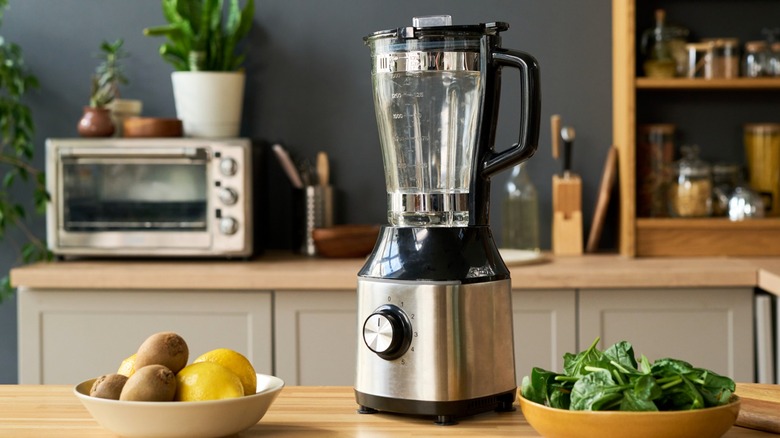 Kitchen blender on countertop with fruit and vegetables