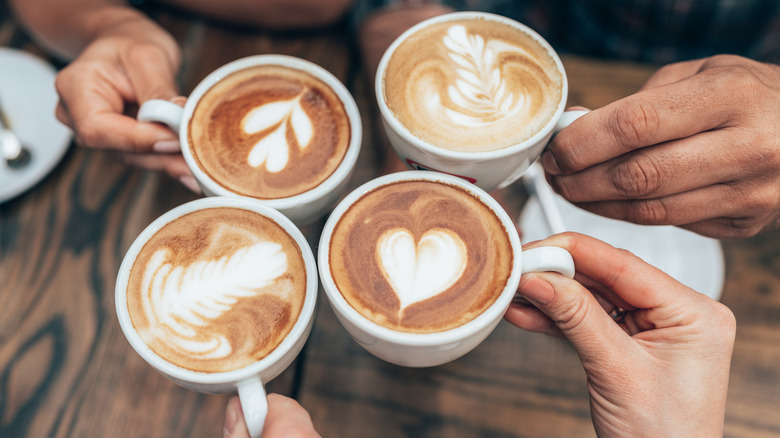 Hands cheersing with mugs full of coffee
