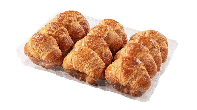 A clear plastic box of 12 golden-brown Member's Mark croissants on a white background displayed at an angle.