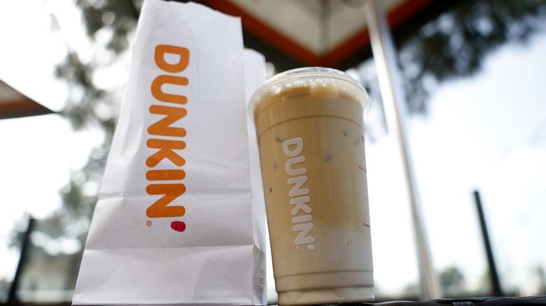 A Dunkin' iced coffee with milk and a Dunkin' food bag, shot from below
