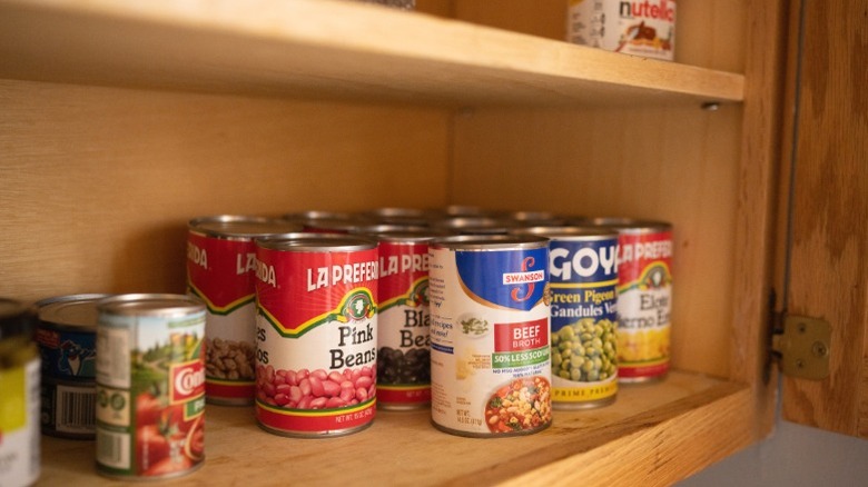 Cans of beans in a pantry.
