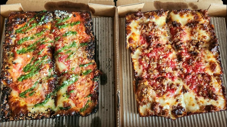 Two rectangular pizzas from Emmy Squared Pizza in two pizza boxes beside one another.