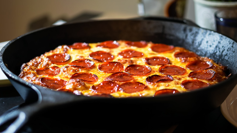 A pepperoni pizza being cooked in a cast iron skillet