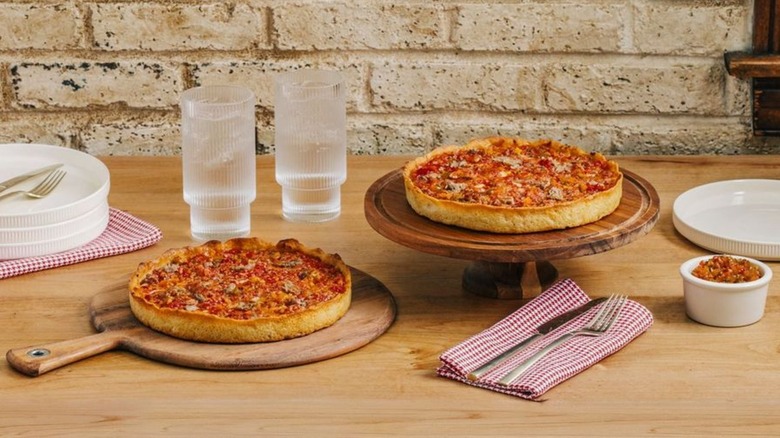 Two specialty deep dish pan pizzas from Lou Malnati's on a table with water glasses and silverware beside them