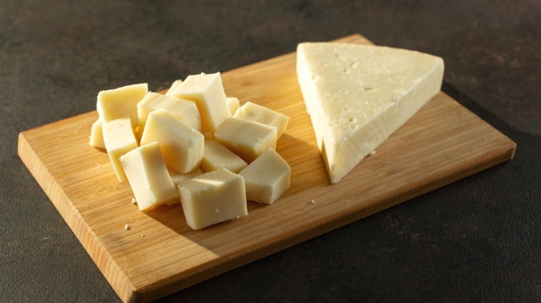 A wedge of fontina cheese next to cubes of fontina.