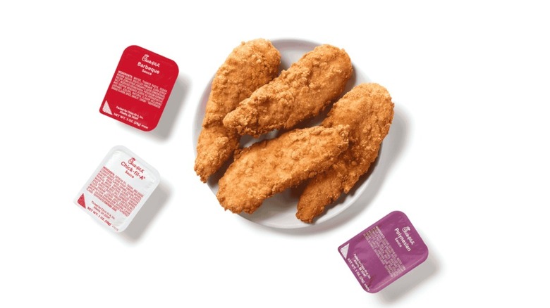 Chick-fil-A chicken strips with dipping sauces near in front of white background