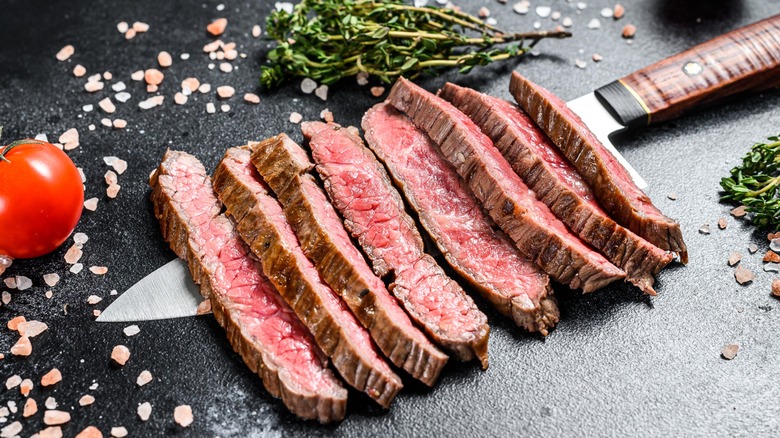 Grilled and sliced fat iron steak on top of knife