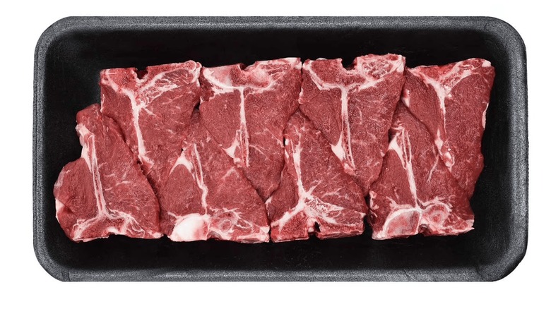 Raw Australian lamb loin chops in black Styrofoam on a white background.