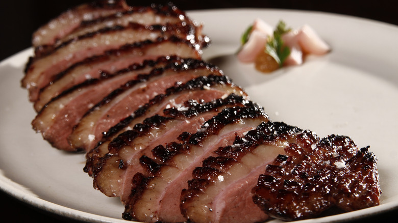 Sliced dry-aged duck breast on a round white plate