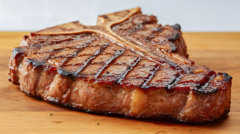 A closeup of a T-bone steak on a wooden board