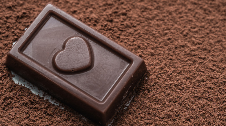 A square of dark chocolate with a heart on chocolate flakes