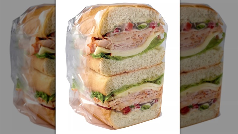 Halved Hill Country Fare Jalapeño Turkey & Asadero Cheese Torta wrapped in plastic on a white background