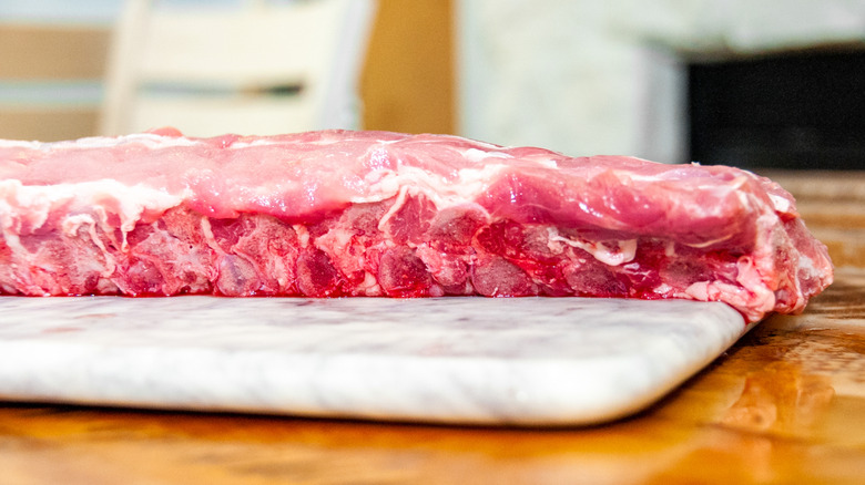 Raw St. Louis pork ribs on marble cutting board