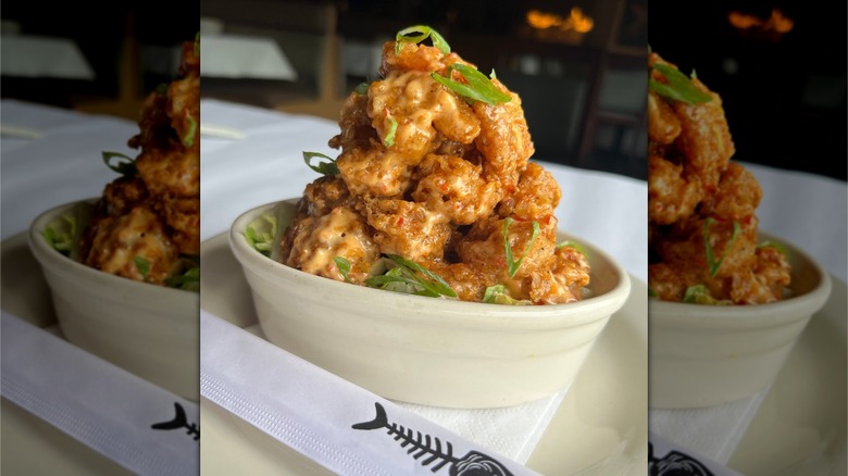 A bowl of breaded, fried shrimp piled high and dressed with green onion at a Bonefish Grill restaurant.