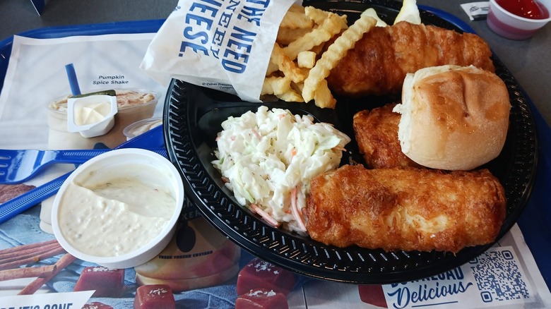 A Culver's fish & chip dinner on a black plastic plate on a restaurant tray