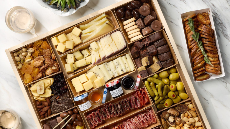 A selection box of sliced meats, cheeses, and nibbles presented on a table