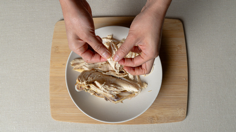 hands shredding chicken meat