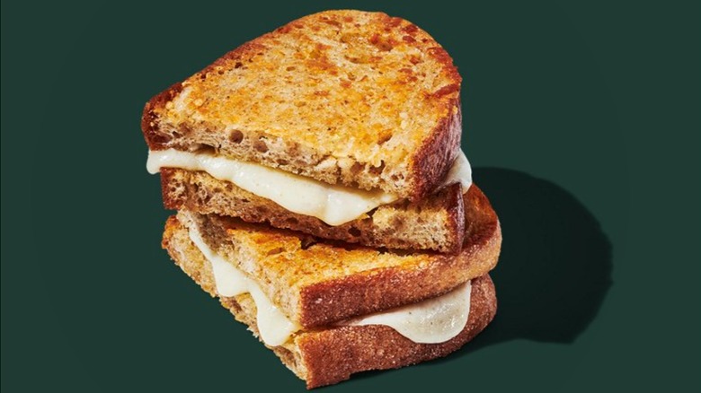 Starbucks Grilled Cheese on Sourdough halves stacked on top of one another in front of dark green background