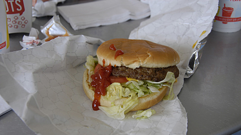 A Sonic burger sits on a table, dripping in sauce
