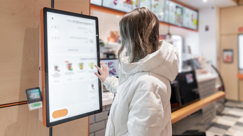 A customer ordering food on a kiosk inside of a fast food restaurant