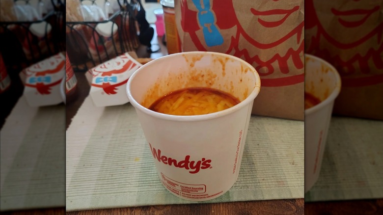 A cup of Wendy's Chili in front of a Wendy's paper bag