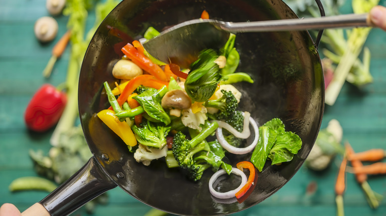 Spatula tossing cooked mixed vegetables in carbon steel pan