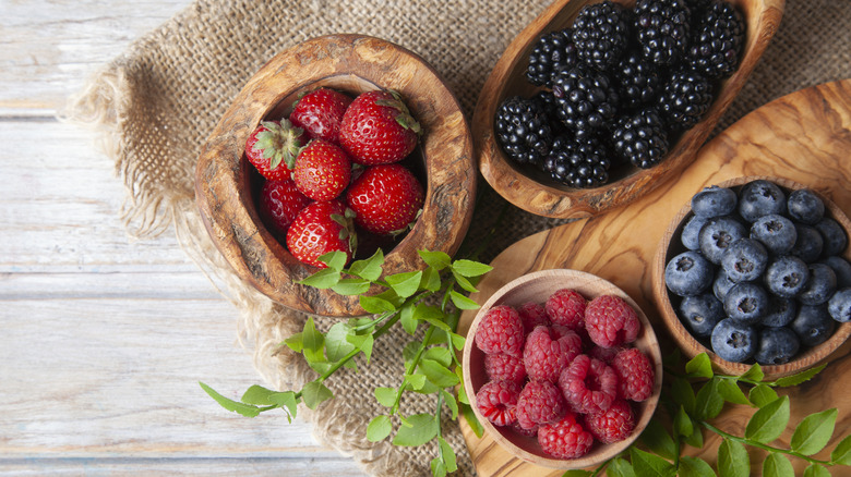 Top view of assorted fresh berries in small wooden bowls