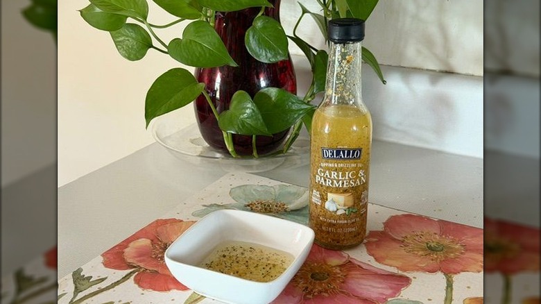 A bottle of Delallo garlic-infused olive oil next to a small bowl filled with oil.