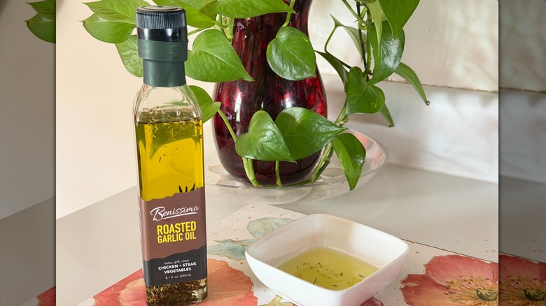 A bottle of Benissimo garlic-infused olive oil next to a small bowl with oil in it.