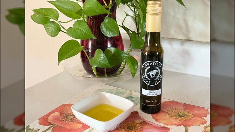 A bottle of Saratoga garlic olive oil next to a small bowl with oil in it.