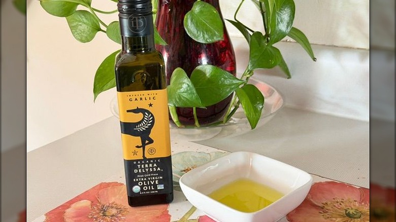 A bottle of Terra Delyssa garlic-infused olive oil next to a small bowl with oil in it.